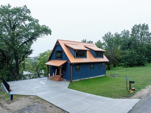 Une maison à deux étages, dotée d’un toit en pente, d’un porche à l’avant et d’une porte d’entrée bien visible.