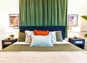 A neatly made bed with a patterned bedspread, a dark headboard, and multiple pillows in various colors and patterns. - Oak Lawn 3BR Townhome | Private Yard & Pool Table (Dallas)