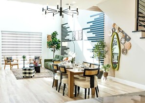 A modern dining area with a wooden table, chairs, and a chandelier. - Oak Lawn 3BR Townhome | Private Yard & Pool Table (Dallas)