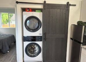 Lavanderia funzionale con lavatrice e asciugatrice a carica frontale, una porta a battente in stile rustico e un frigorifero sul lato destro.