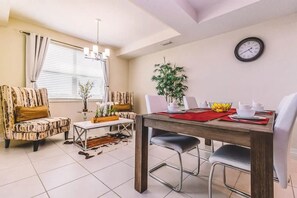 A dining area with a wooden table, chairs, and a clock on the wall. - Modern 2BR Condo Near Disney w/ Resort Amenities (Kissimmee)