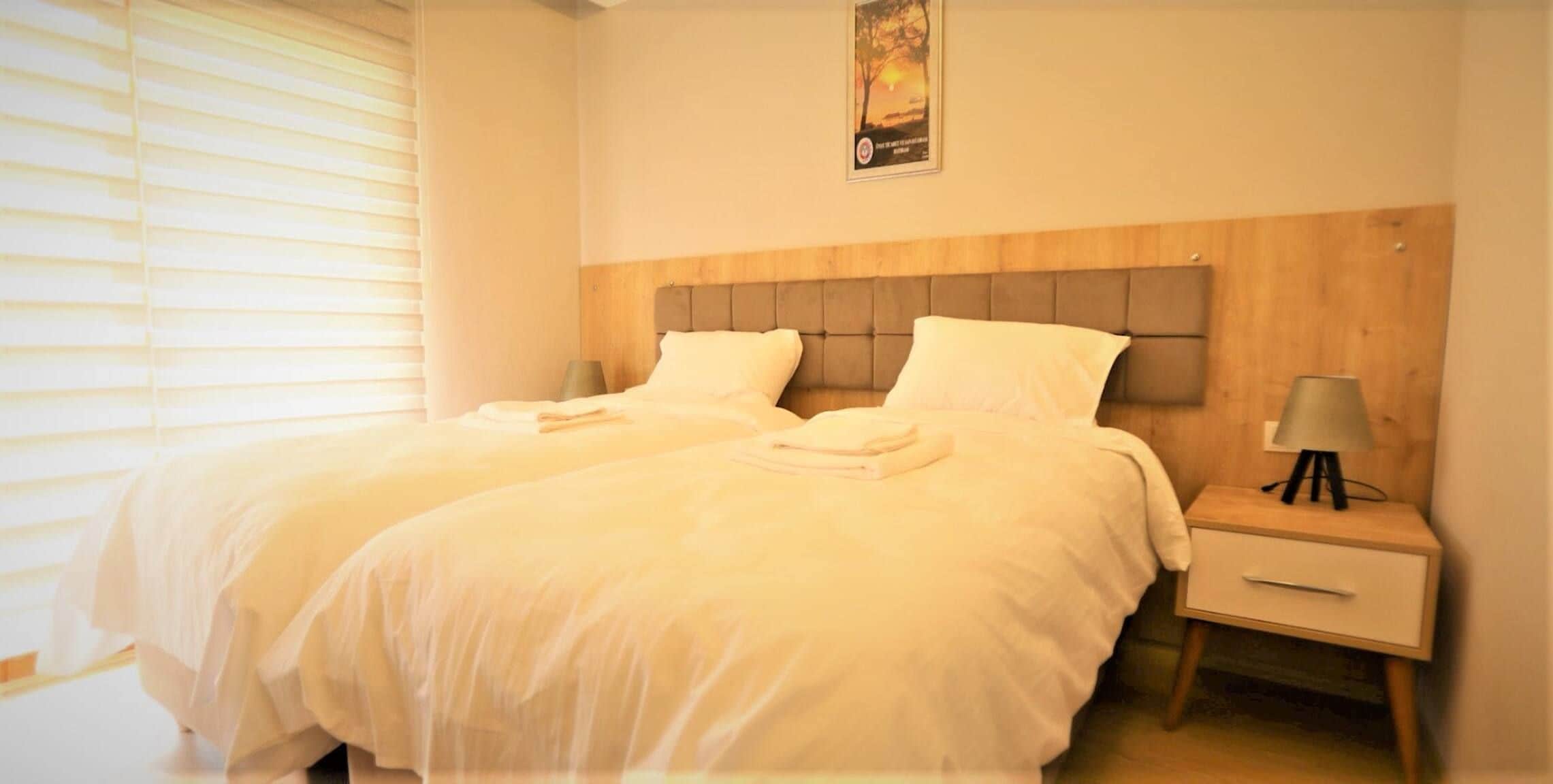 A hotel room with two beds, a nightstand, and a poster on the wall.