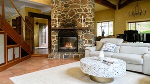 A living room with a stone fireplace, a round coffee table, and a staircase. - Tanglin - Mount Macedon (Mount Macedon)
