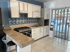 A kitchen with white cabinets, a granite countertop, a gas stove, and a sink. - 4-bedroom townhome in lovely Puerto Morelos with AC and jacuzzi for 8 (Puerto Morelos)