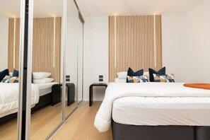 A modern hotel room with a large bed, a bedside table, a mirror, and a wooden slat wall design. - Luxury & Style in the Heart of Auckland Opp Train Station (Auckland CBD)