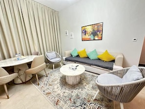 A modern living room with a sofa, chairs, a coffee table, and a dining table. - 1BR Sparkle Tower Dubai Marina (Dubai)