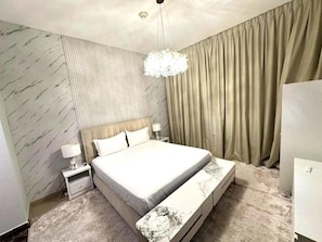 A bedroom with a bed, nightstands, a lamp, a chandelier, and a large window with curtains. - 1BR Sparkle Tower Dubai Marina (Dubai)