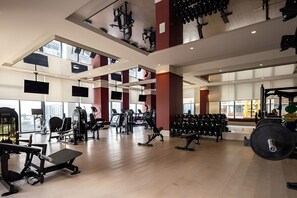 A spacious gym with various exercise equipment, large windows, and a high ceiling. - Modern Downtown Miami Apt w/ Balcony (Miami)