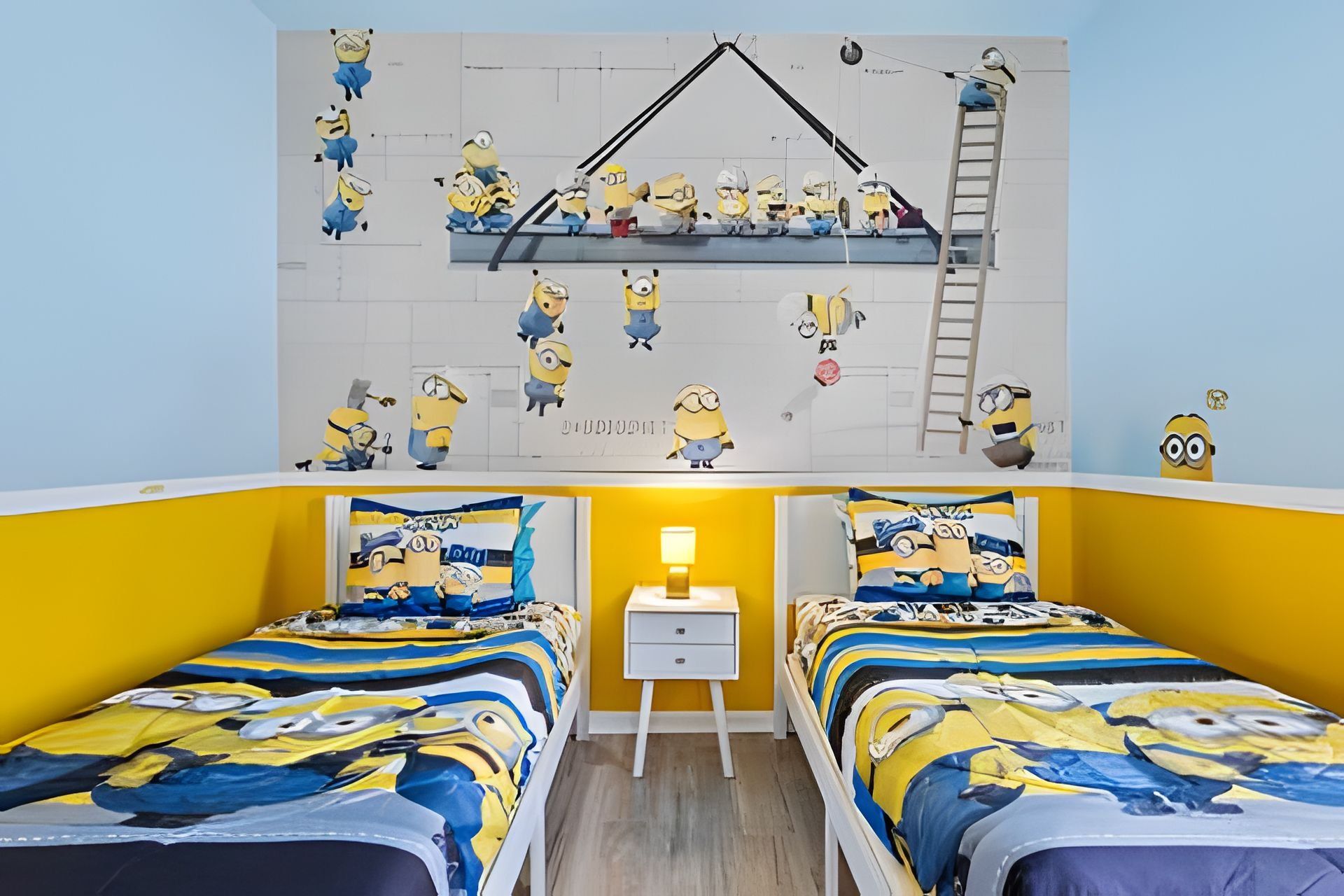 Ett rum med två sängar, ett nattduksbord och en vägg som är dekorerad med figurer från filmen Minions.