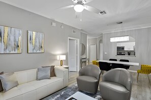 A modern living room with a white sofa, two armchairs, and abstract art on the wall. - Family-friendly 3BR Near Disney! (Kissimmee)