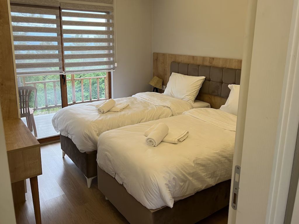 A bedroom with two beds, a wooden headboard, a desk, and a chair.
