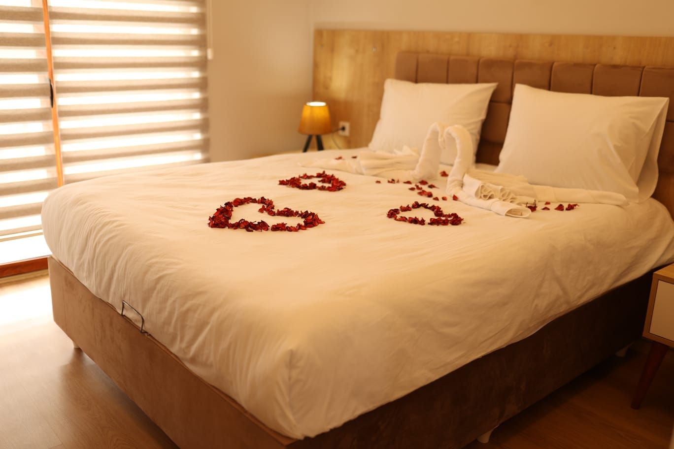 Una cama bien hecha con sábanas blancas y pétalos de rosa decorando el lecho.