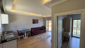 Ein modernes Wohnzimmer mit Sofa, Esstisch und Küchenzeile inklusive Wasserkocher.
