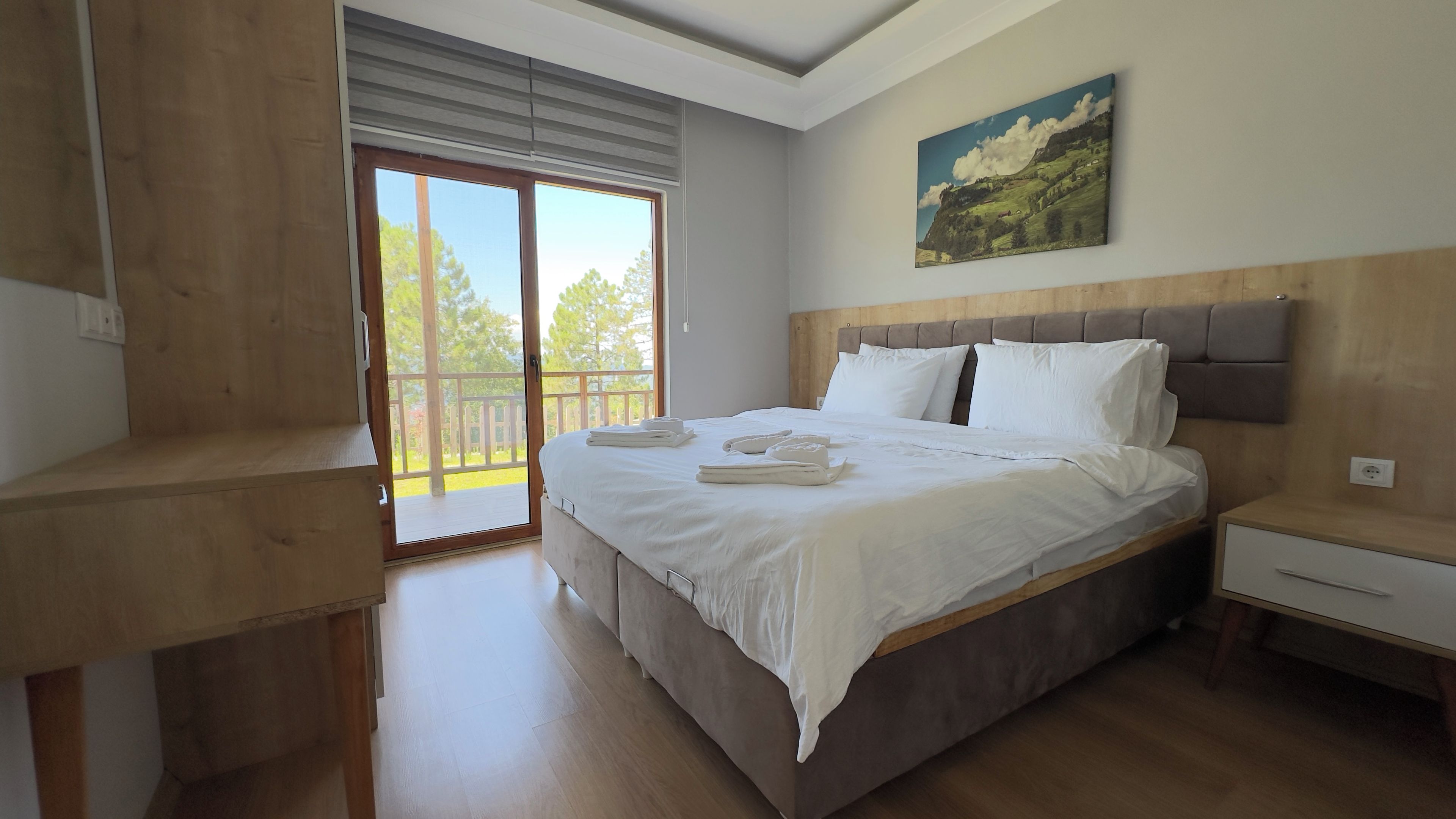 Un dormitorio con una cama grande, cabecera de madera, mesita de noche y un cuadro en la pared.
