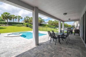 A covered patio with a swimming pool, outdoor furniture, and a view of the surrounding landscape. - Luxury 8BR Family Home Near Disney at Encore 54MA (Kissimmee)