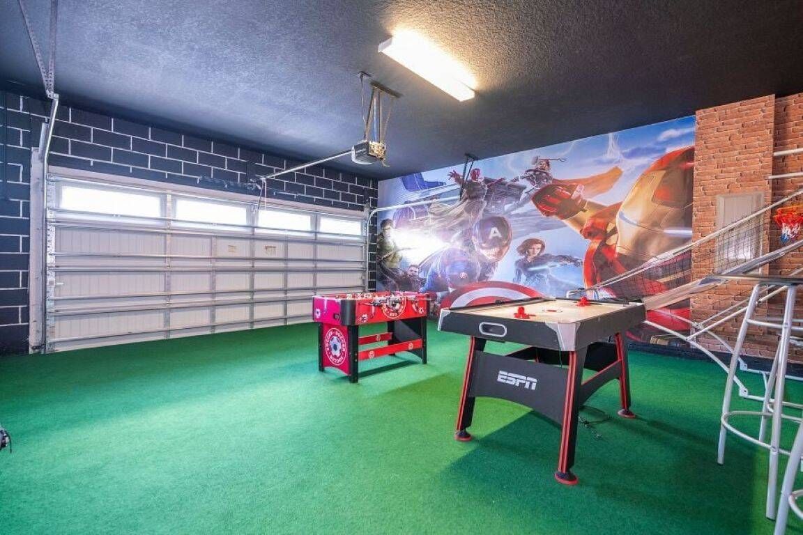 A room with a foosball table, a pool table, and a mural on the wall.