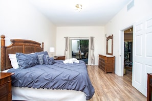A bedroom with a large bed, wooden headboard, and a dresser. - Modern Family Condo 15min From Disney (Kissimmee)