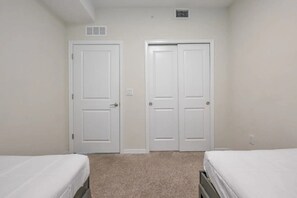 A bedroom with two single beds, a carpeted floor, and two white doors. - Cozy 2BR Condo 10 Min to Disney Pool (Kissimmee)