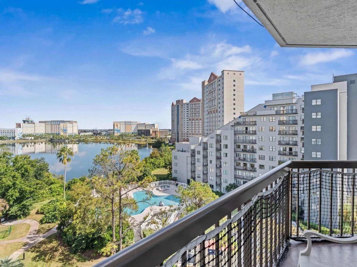 A high-rise building with a swimming pool and a lake in the background.
