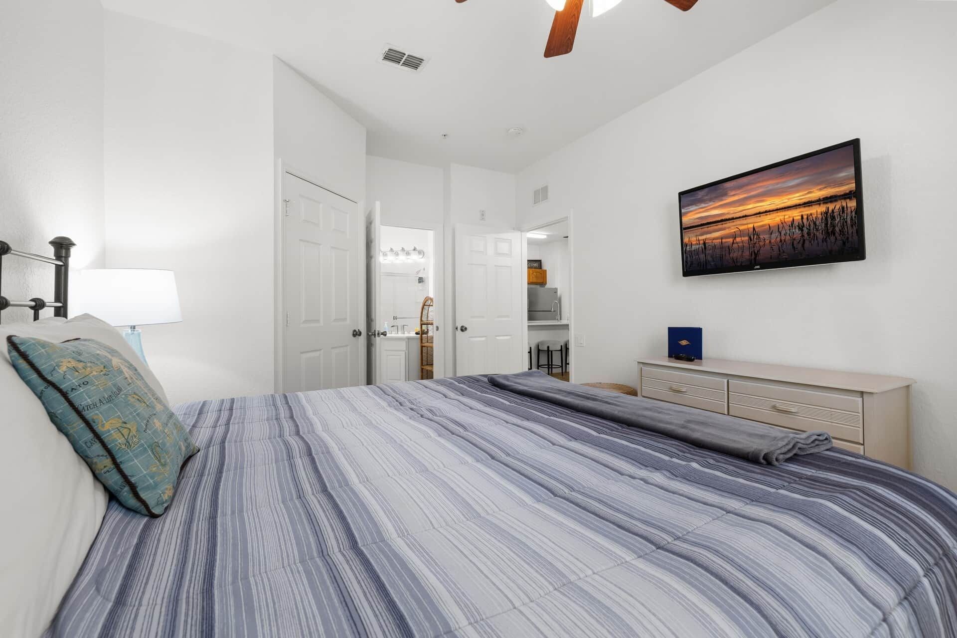 Un dormitorio con cama, cómoda, cuadro y puerta que da a otra habitación.