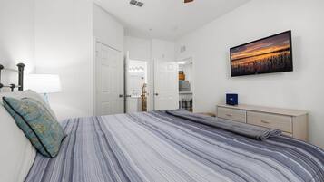 Un dormitorio con cama, cómoda, cuadro y puerta que da a otra habitación.