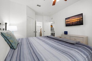 A bedroom with a bed, a dresser, a painting, and a door leading to another room. - Disney Magic in Windsor Hills Resort (Kissimmee)