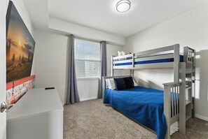 Een slaapkamer met stapelbedden, een bureau, een raam met gordijnen en een poster aan de muur.