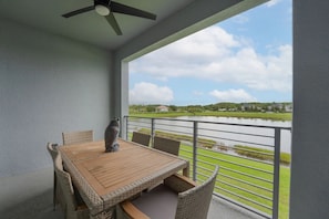 Een balkon met een tafel en stoelen, met uitzicht op een waterpartij en een golfbaan.