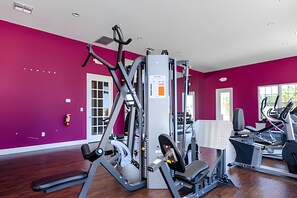 A gym with various exercise machines, a white door, and a window with a view of greenery. - Disney 3BR Townhome w/ Pool & Mickey Theme (Kissimmee)