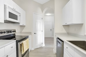A modern kitchen with white cabinetry, a built-in oven, a microwave, and a dishwasher. - Disney 3BR Retreat at Windsor Palms Resort (Kissimmee)