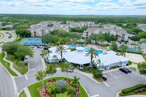 An aerial view of a residential area with multiple buildings, a swimming pool, and a landscaped garden. - Disney 3BR Retreat at Windsor Palms Resort (Kissimmee)