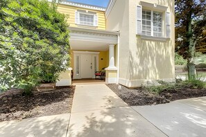 A two-story house with a covered garage, a front porch, and a driveway leading to the garage. - Seven Eagles 3BR Condo Across From Reunion Grande (Kissimmee)