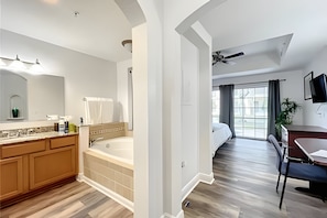 A spacious bathroom with a large bathtub, a vanity with a mirror, and a shower area. - Seven Eagles 3BR Condo Across From Reunion Grande (Kissimmee)