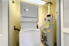 Una sala de bugaderia amb una rentadora i assecadora de càrrega frontal, un acumulador d'aigua i un sistema de ventilació.
