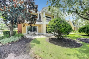 A two-story house with a front porch, a small garden, and a well-maintained lawn. - Seven Eagles 3BR Condo Across From Reunion Grande (Kissimmee)