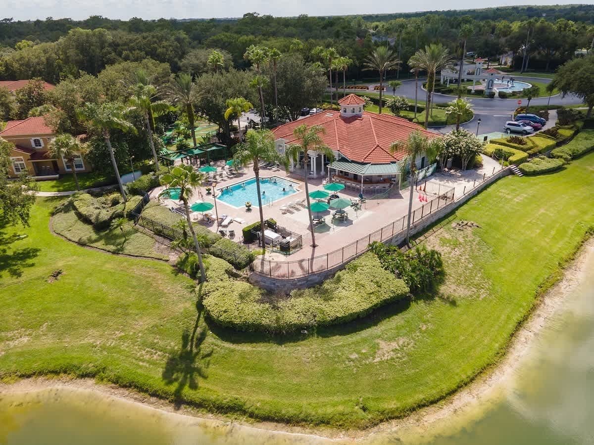 Luchtbeeld van een resort met een centraal zwembad, meerdere ligbedden en een omheind terras.