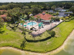An aerial view of a resort with a central pool area, multiple lounge chairs, and a fenced deck. - 3BR Villa in Emerald Island Near Disney (Kissimmee)