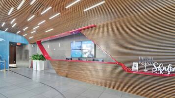 A modern reception area with a sloped ceiling, a reception desk, and a wall-mounted digital screen.