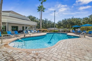 A swimming pool with lounge chairs and a building in the background. - Pool View Suite Near Disney, 1BR Comfort (Orlando)