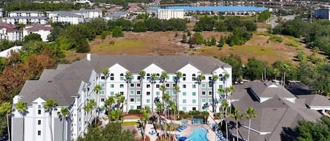 A hotel with multiple buildings, a swimming pool, and surrounding greenery.