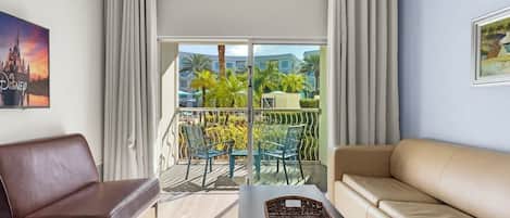 Een hotelkamer met balkon, een bank, een stoel en een tafel met dienblad.