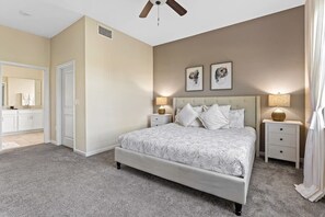 A bedroom with a bed, nightstands, a ceiling fan, and a large mirror. - 2BR Golf View Condo + Champions Gate Resort (Davenport)