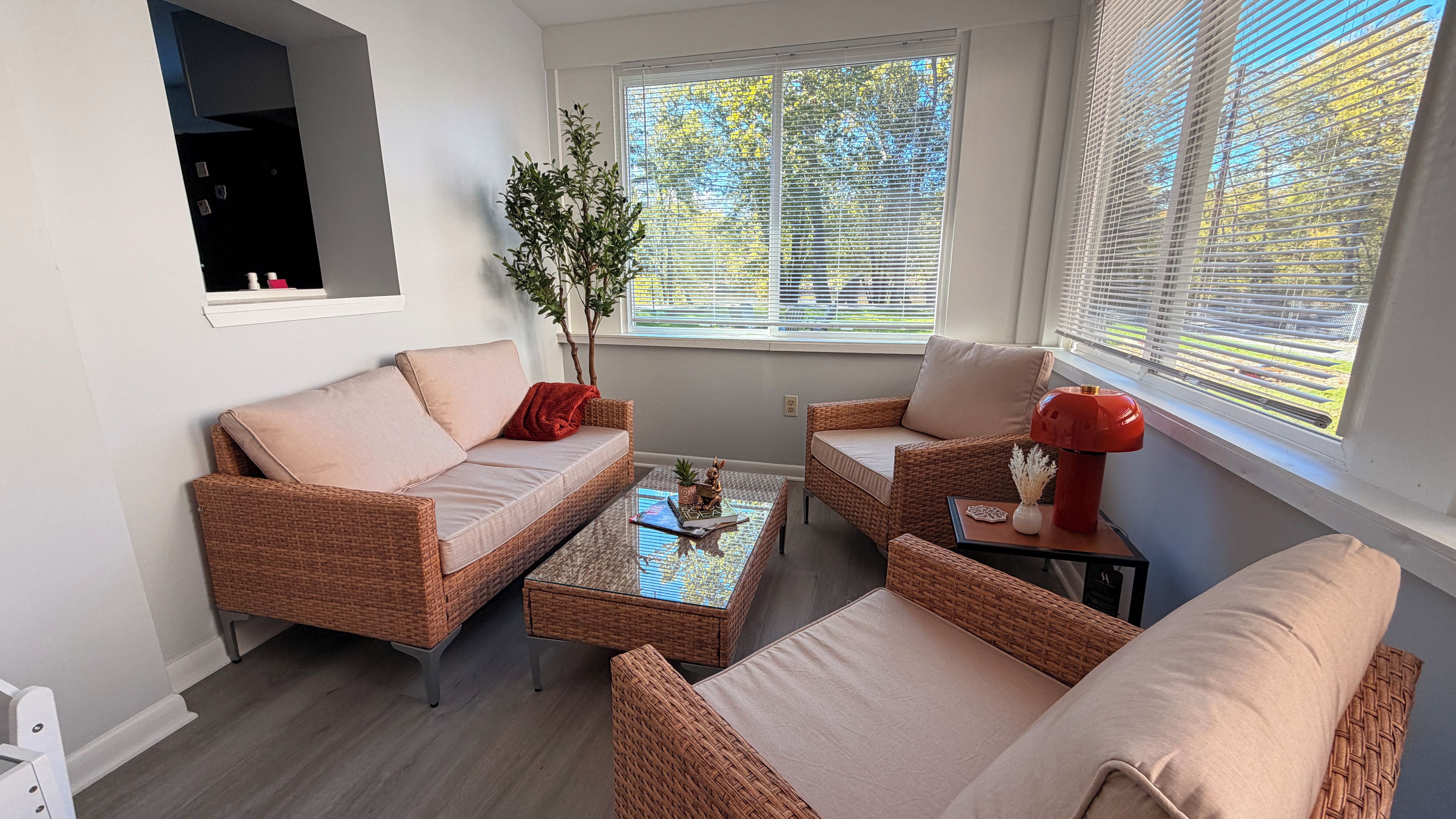 Ein modernes Wohnzimmer mit einer Couch, zwei Sesseln, einem Couchtisch und einem Beistelltisch mit Dekoration.