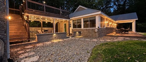 A modern house with a covered patio, outdoor seating, and a stone pathway leading to the entrance.