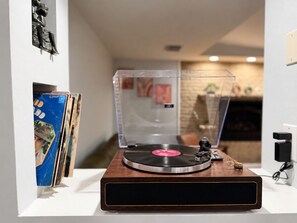 A turntable with a transparent cover, a vinyl record, and a small figurine on a wooden base. - Willow Terrace House (Mechanicsburg)