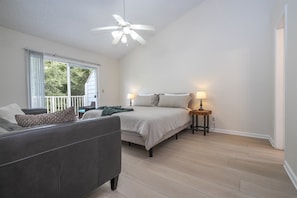 Ein Schlafzimmer mit Bett, einer Couch, einer Stehlampe und einem Deckenventilator.