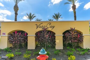 The entrance of Vista Cay Resort with a yellow facade, arched doorways, and tropical plants. - 3BR Vista Cay Condo Near Universal (Orlando)