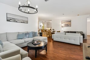 A modern living room with a sofa, a coffee table, and a chandelier. - 3BR Vista Cay Condo Near Universal (Orlando)