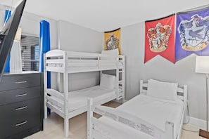 A bedroom with bunk beds, a dresser, and two flags on the wall. - Modern 2-bedroom Enclave Condo Retreat (Orlando)