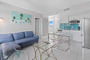 A modern kitchen with white cabinets, a stainless steel refrigerator, and a blue-tiled backsplash. - Modern 2-bedroom Enclave Condo Retreat (Orlando)